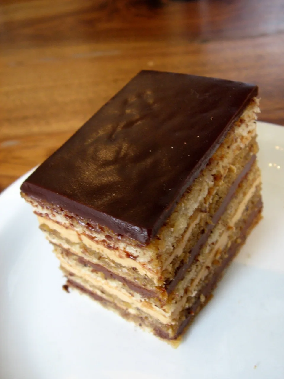 A slice of opéra showing its coffee and chocolate layers.