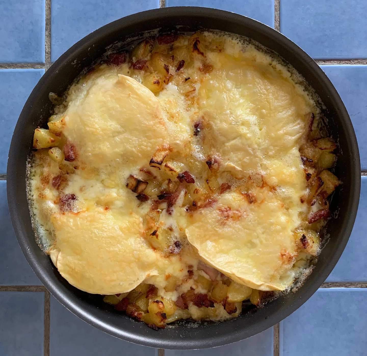 Tartiflette with melted Reblochon in a round baking dish.