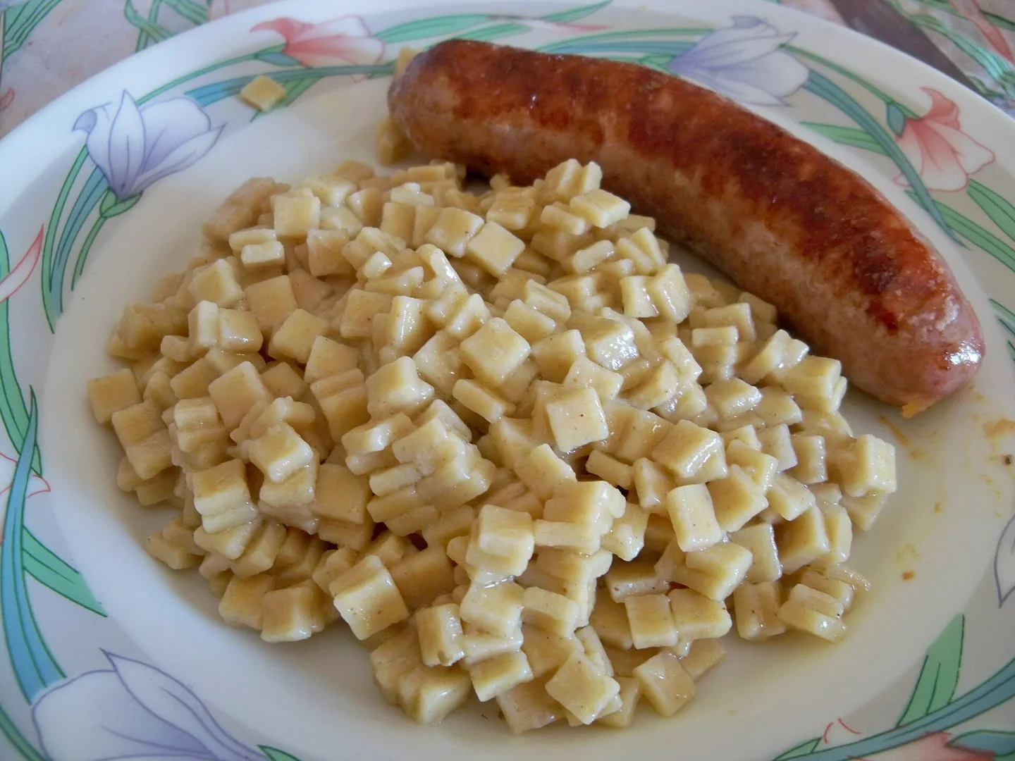 Cooked crozets served with sausage.