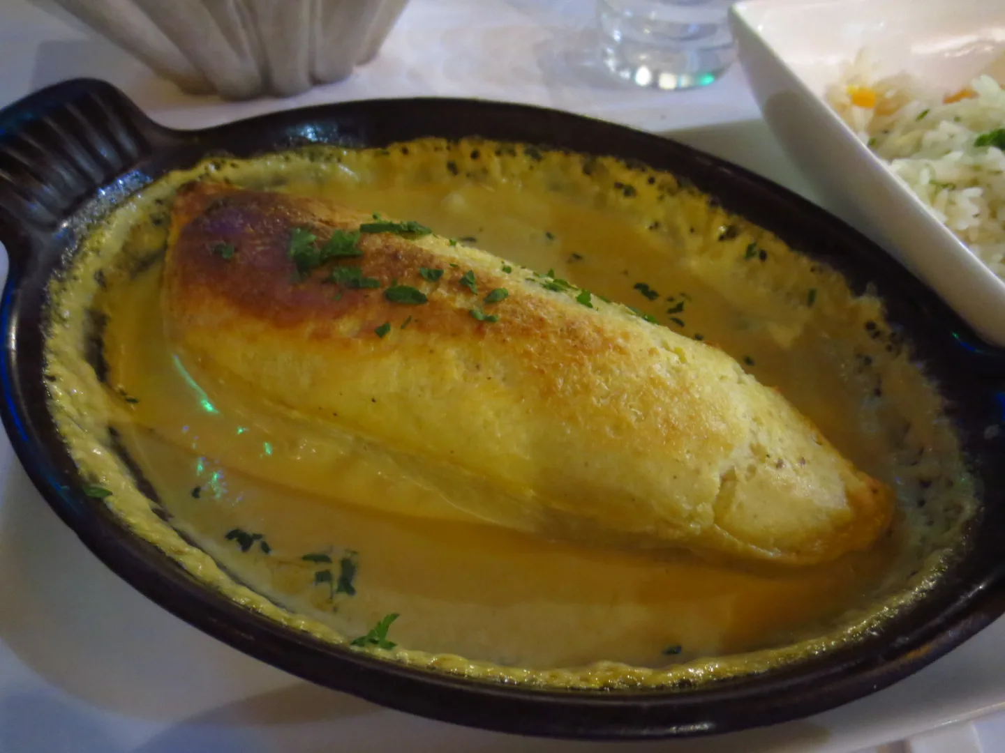 A pike quenelle served in sauce in a baking dish.
